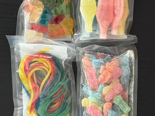 Assorted gummy candies in clear sealed bags, including gummy bears, sour gummies, cola bottles, and candy strings.