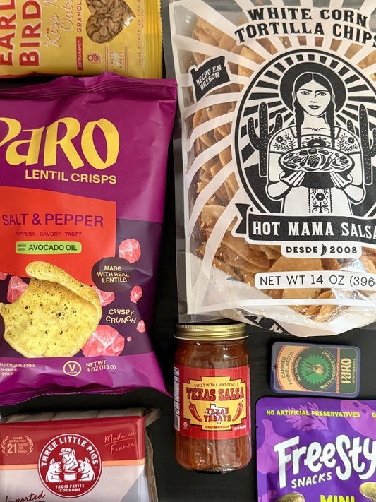 Assorted gourmet snack foods including tortilla chips, salsa, lentil crisps, and granola.