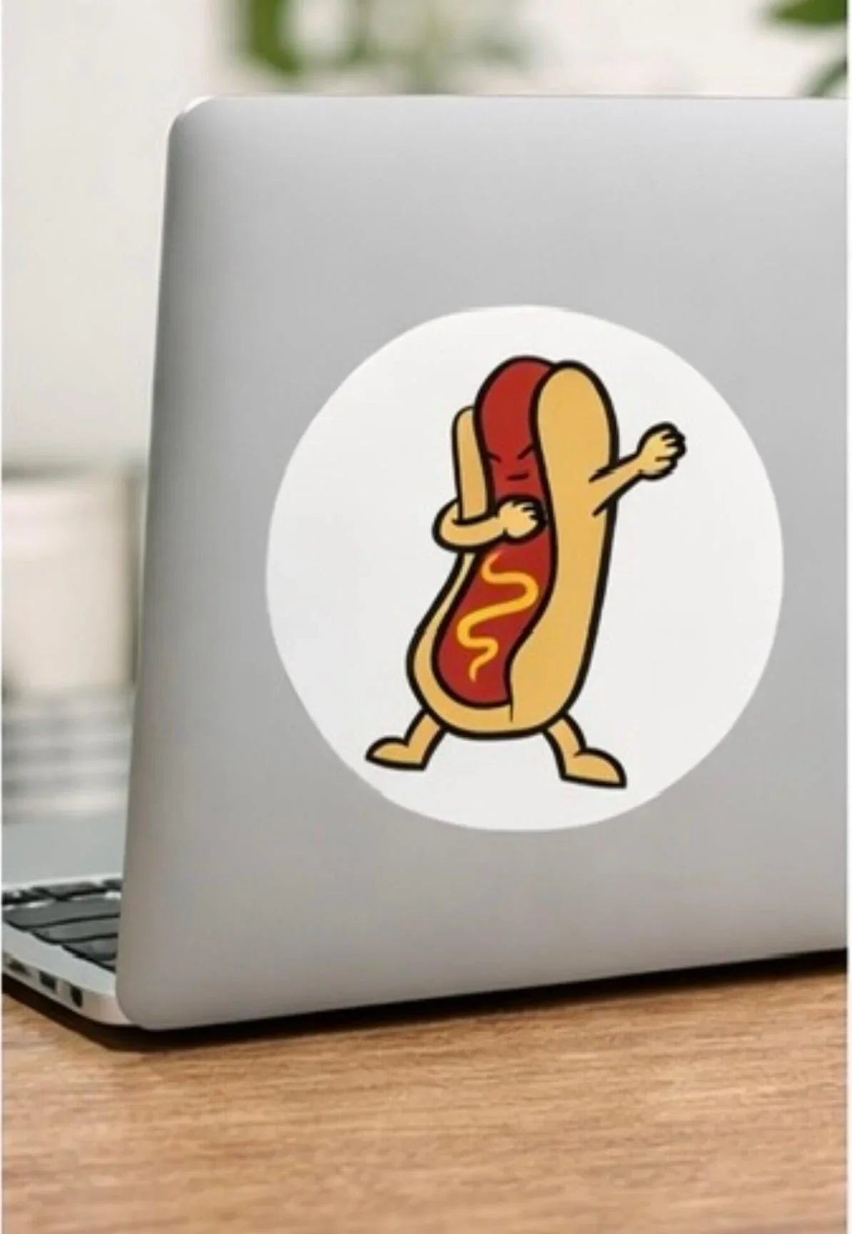 funny hot dog dabbing sticker on silver laptop, novelty laptop decal on wood desk
