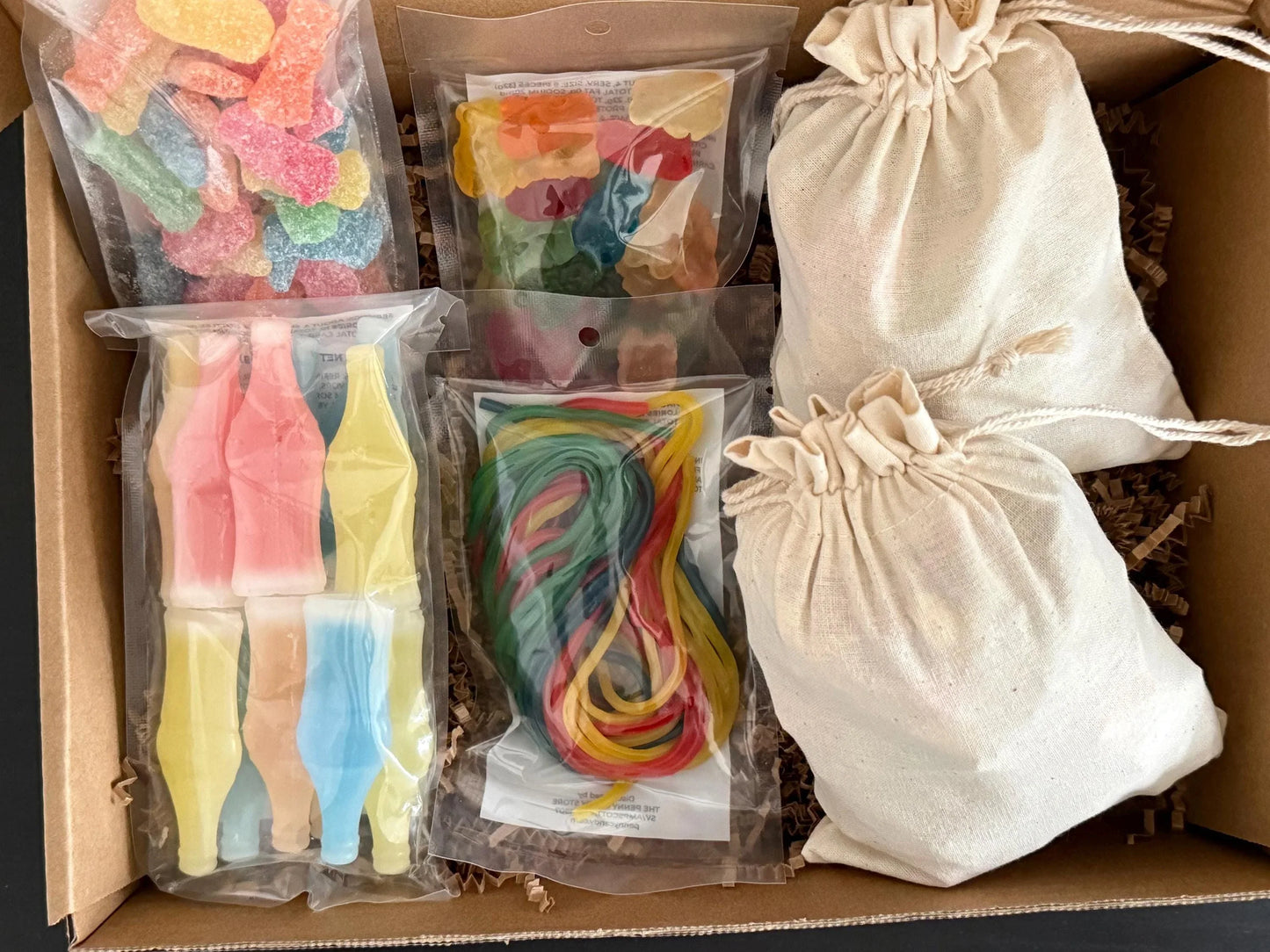 Gift box with assorted gummy candies, rainbow licorice, and cream drawstring bags