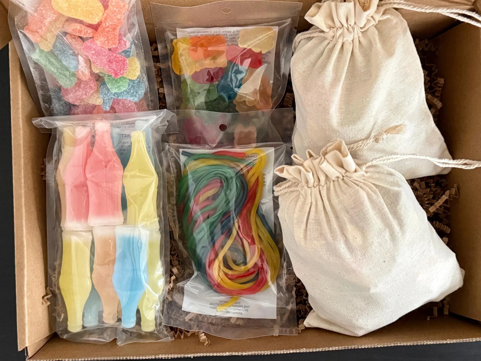 Gift box with assorted gummy candies, rainbow licorice, and cream drawstring bags