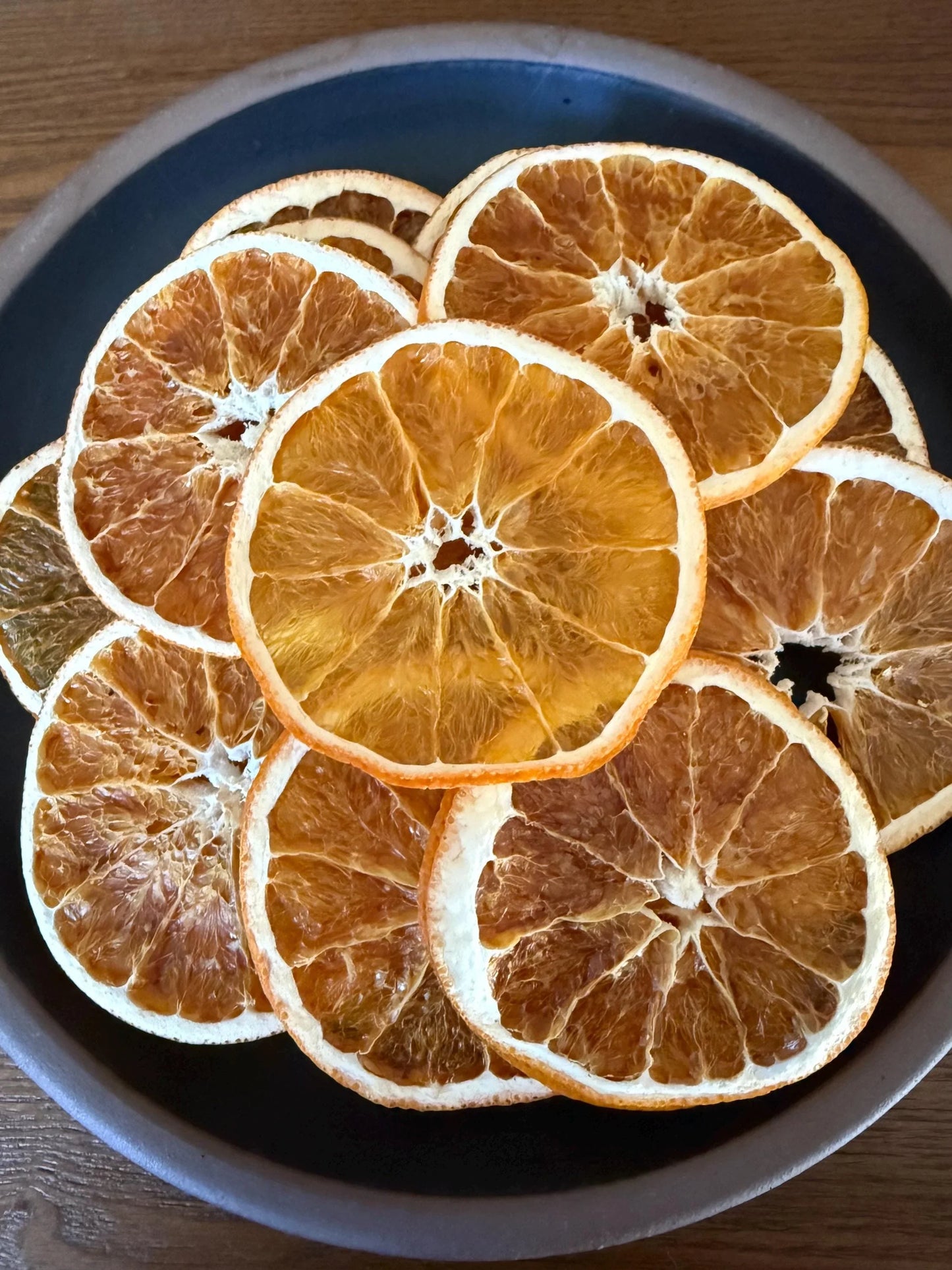 Bowl of dried orange slices, gourmet snack or cocktail garnish on a wooden table