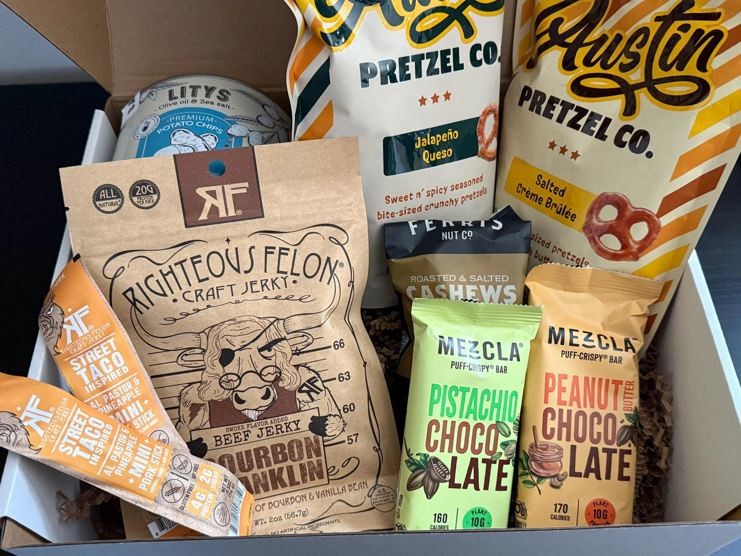 Assorted gourmet snack gift box with jerky, pretzels, nut bars, chips, and cashews