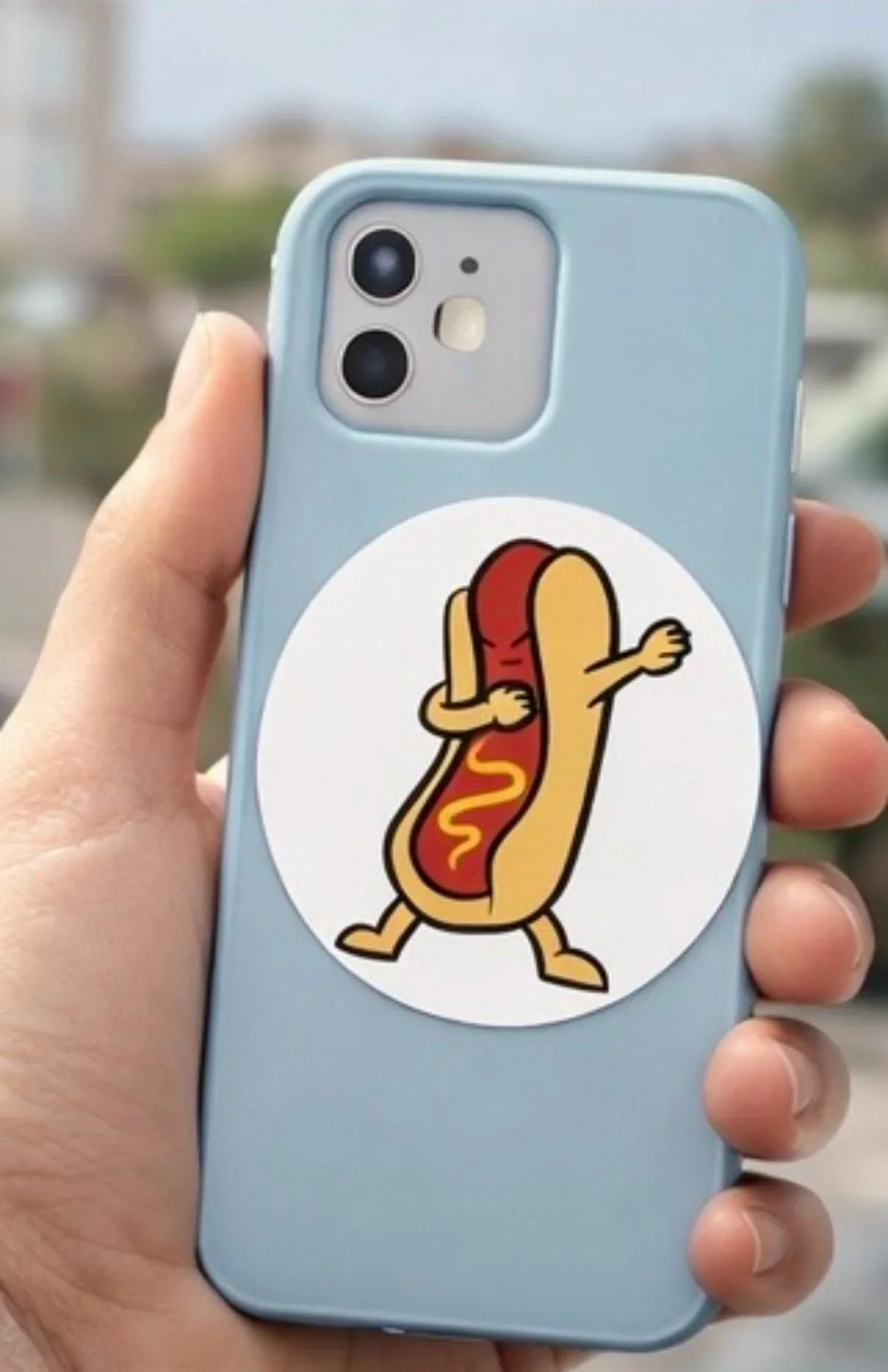 Blue phone case with a cute dabbing hot dog sticker held in a hand, fun novelty accessory