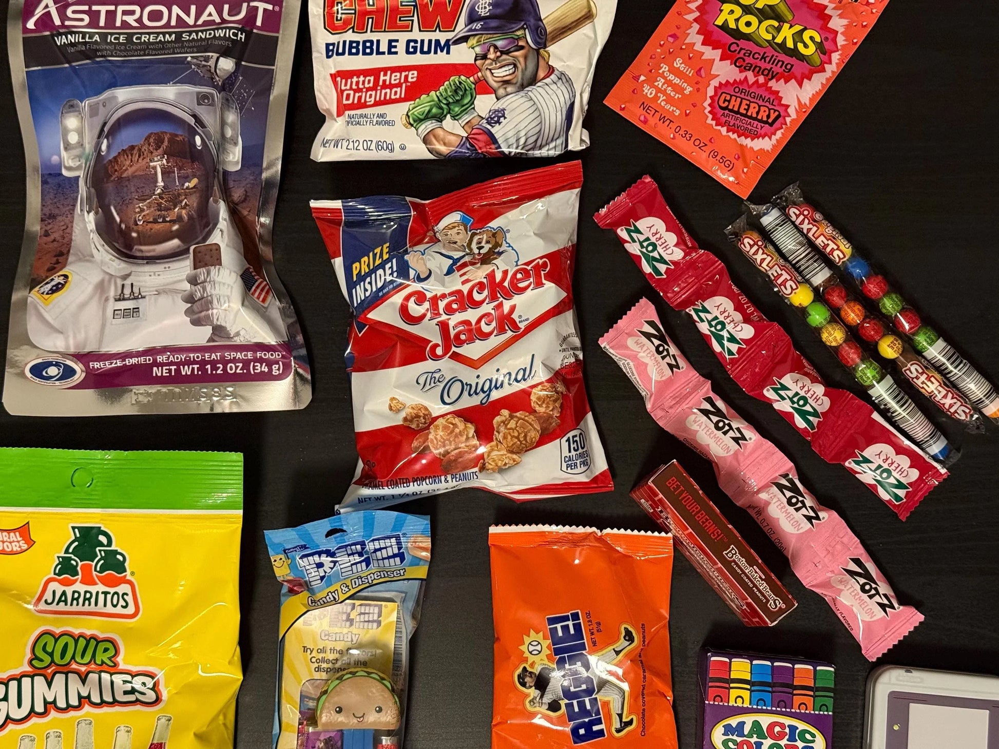 Assorted nostalgic candies and snacks including Cracker Jack, Astronaut ice cream, and PEZ dispenser
