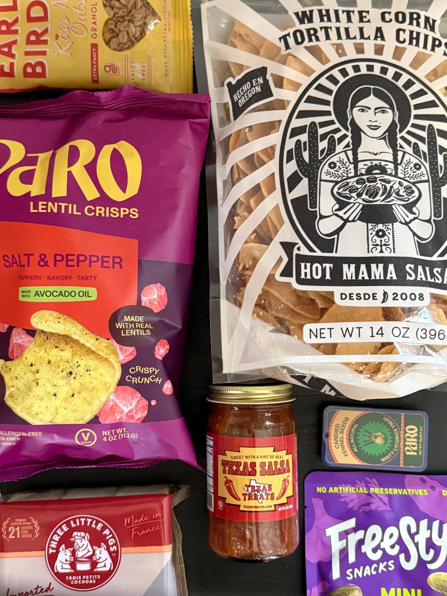 Artisan snack assortment with lentil crisps, tortilla chips, salsa, and gourmet treats.