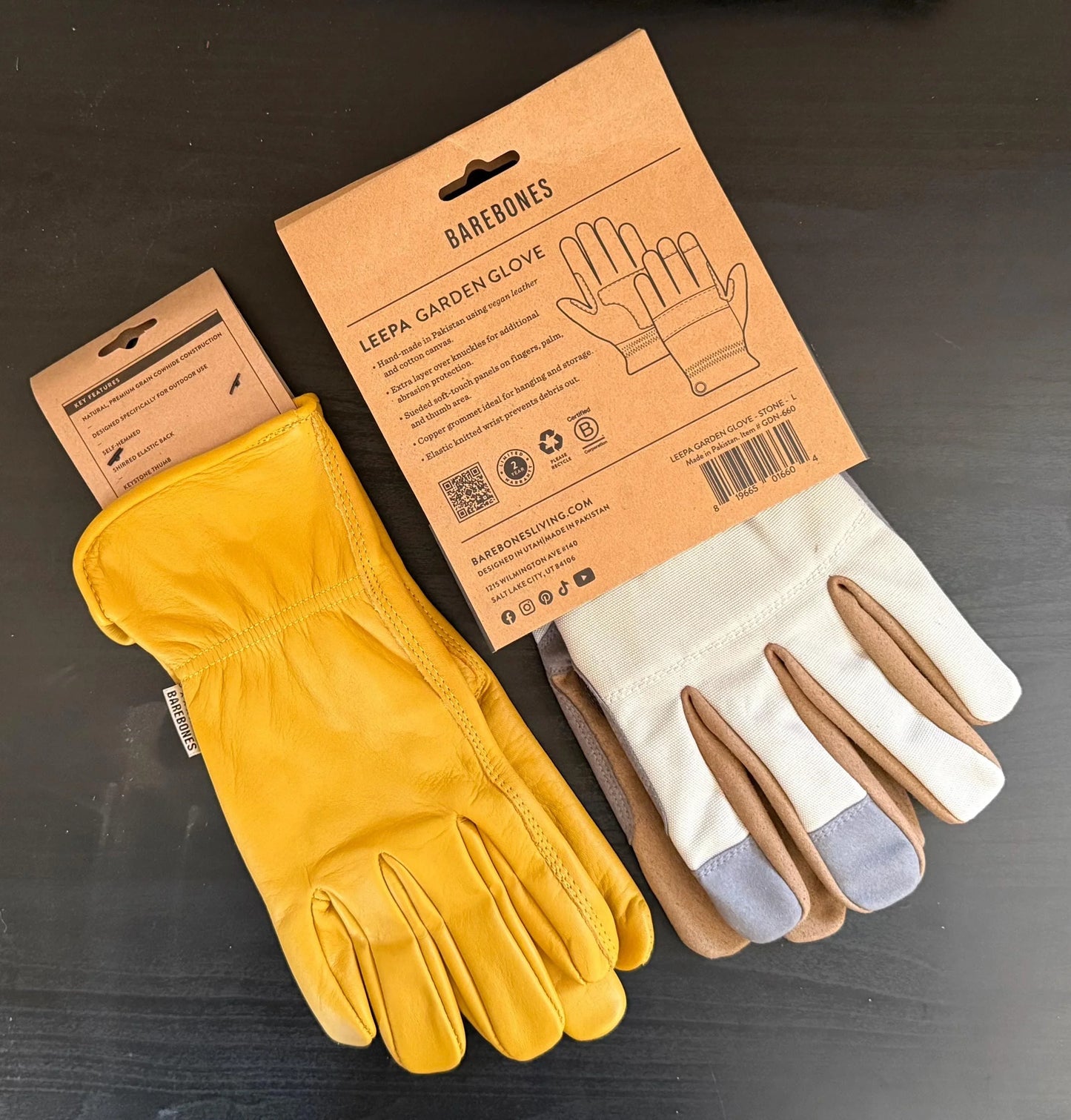 Leather and fabric garden gloves with Barebones packaging on a dark surface