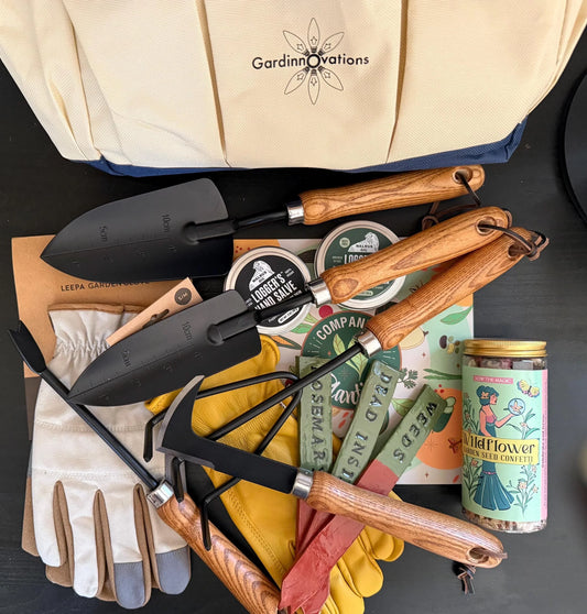 Garden tool set with gloves, plant markers, hand salve, and wildflower seed jar on table