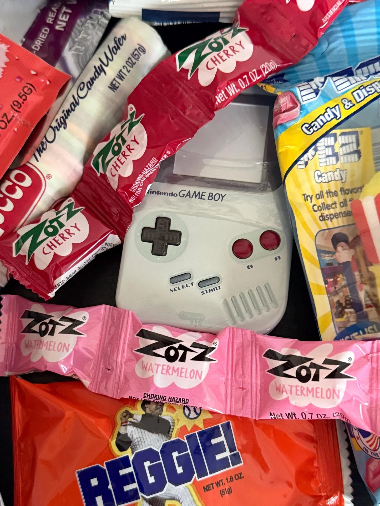Assorted nostalgic candies with Zotz, Reggie bar, and Game Boy toy in a gift box