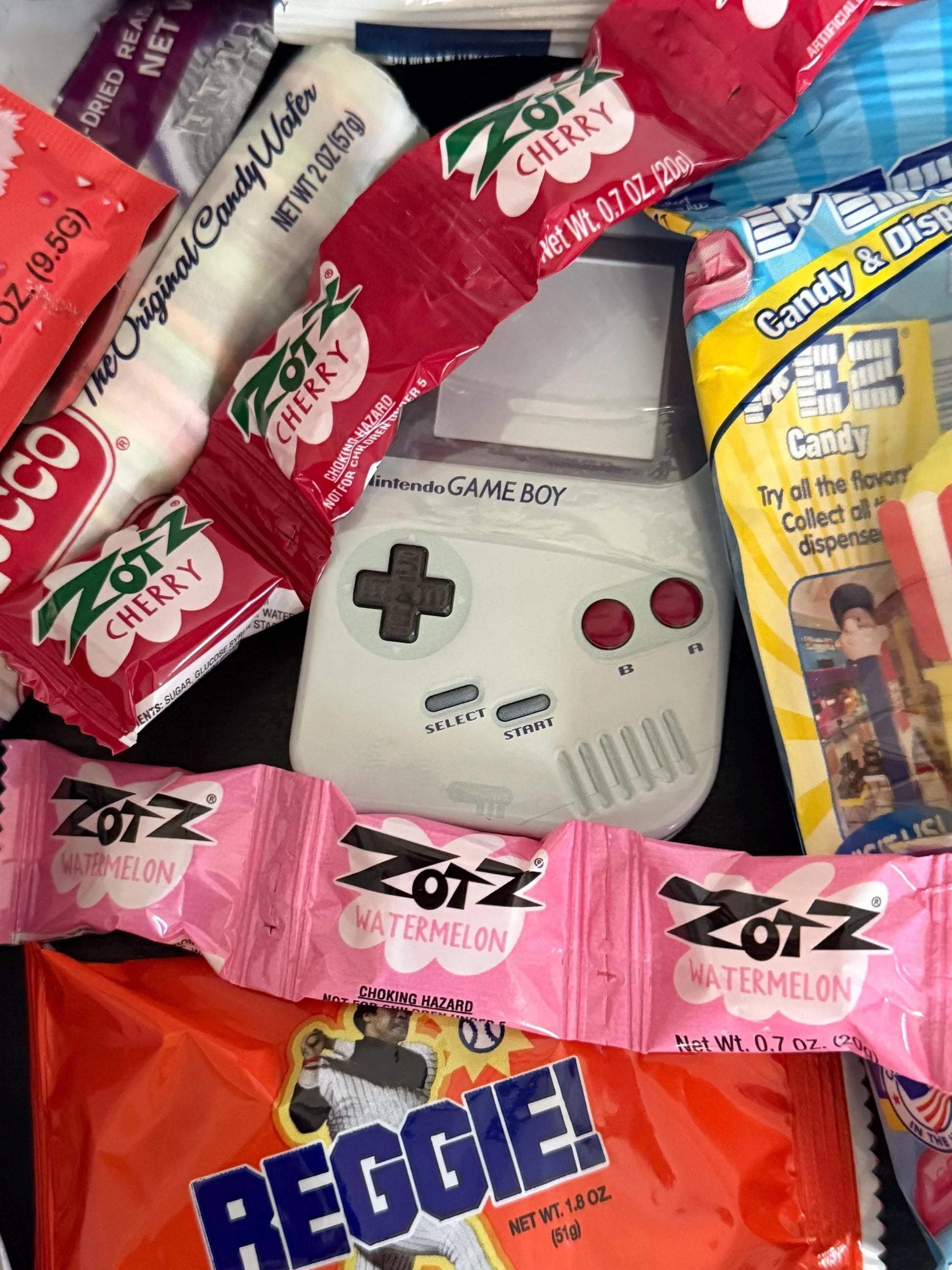 Assorted nostalgic candies with Zotz, Reggie bar, and Game Boy toy in a gift box