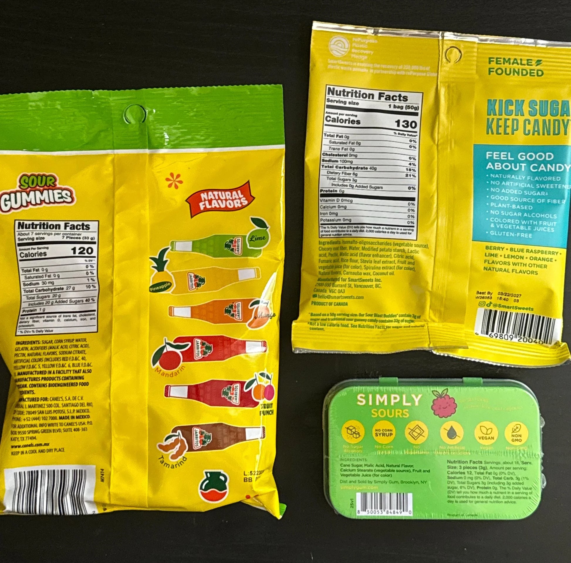 Assorted sour gummies and sours candy packages with nutrition facts on a black background