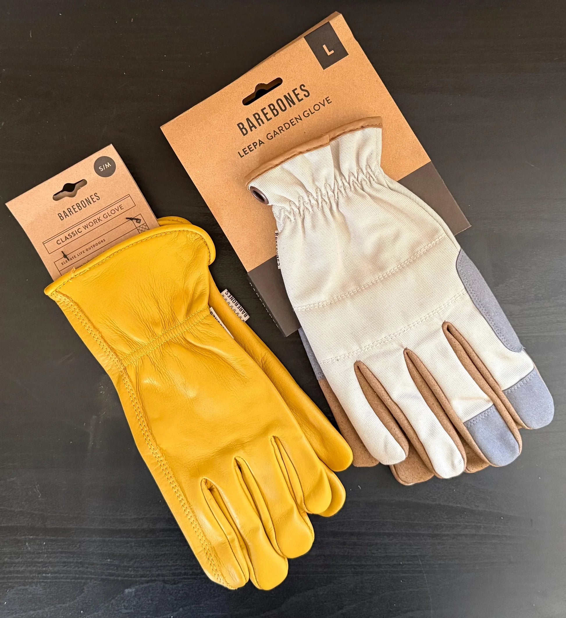 Barebones work glove and Leepa garden glove in yellow leather and beige fabric on black table