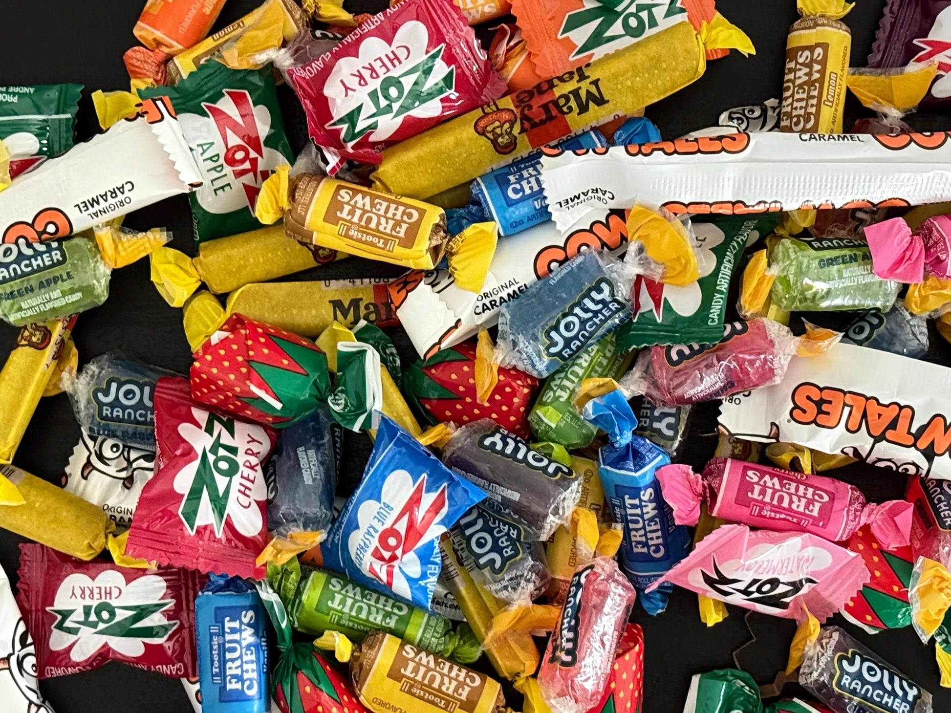 Assorted wrapped candies including Jolly Rancher, Zotz, Cow Tales, and Tootsie Fruit Chews
